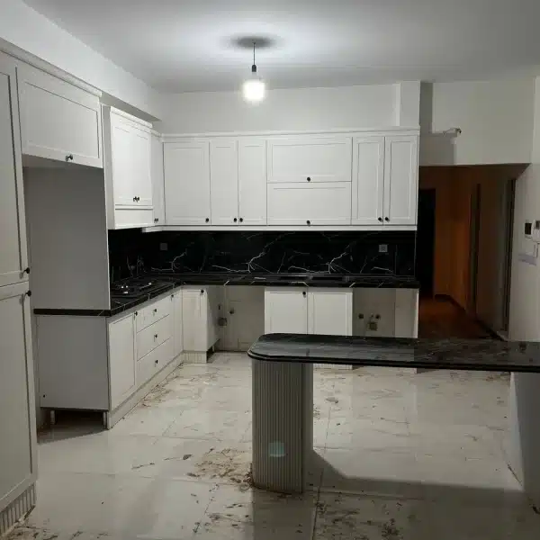 آشپزخانه مدرن در پروژه قلعه حسن خان با کابینتهای سیانسی کف تراش، روکش سوپرمات کرهای و صفحه سنگ رگهدار مشکی