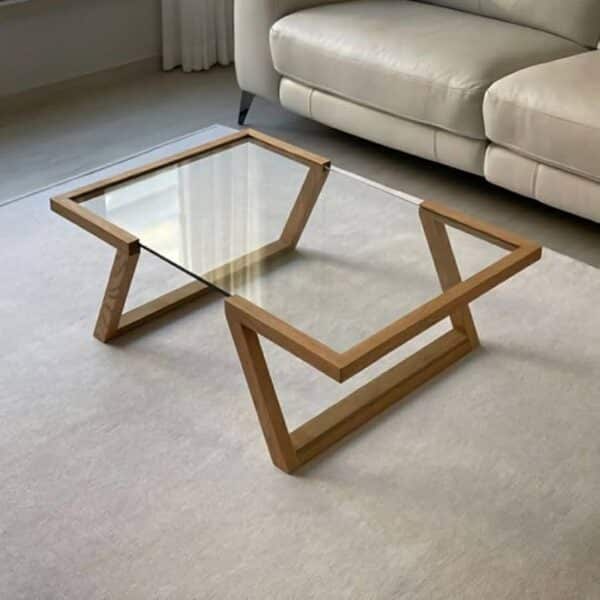میز جلو مبلی مدرن با پایه چوب طبیعی زاویه‌دار و صفحه شیشه‌ای شفاف – مدل زاورا